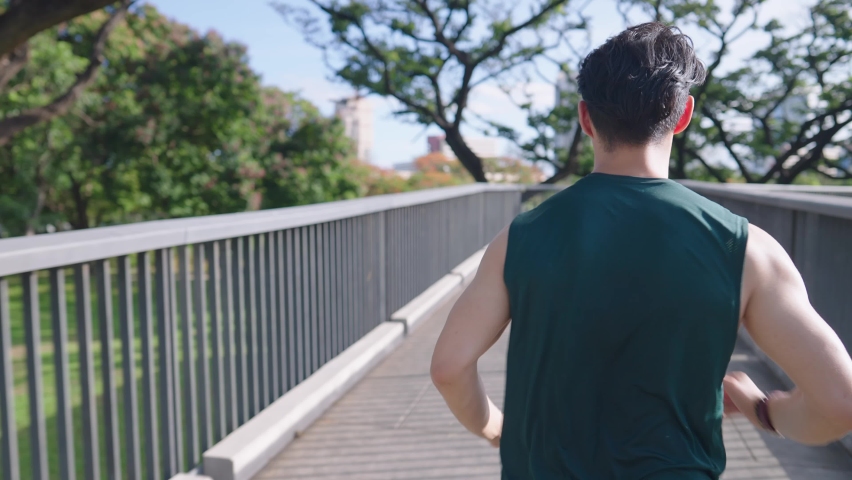 Rear follow shot of Young strong man running alone on the modern urban pathway, overheat heat stroke caution in the hot summer, self discipline stay fit and firm, burning calories for healthy body Royalty-Free Stock Footage #1091318017