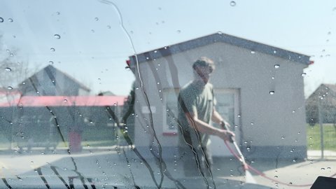 Man washing car in self-service carwash garage with high-pressure jet sprayer, selective focus