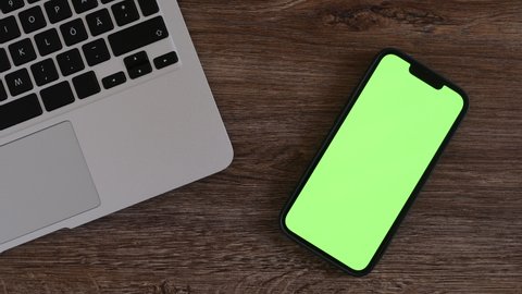 Smartphone mockup green screen on freelancer's work desk, top view flat lay