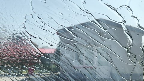 Self-service car wash with jet sprayer, water and soap on vehicle windscreen, selective focus
