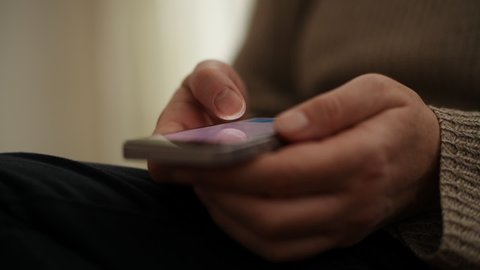 Closeup of female hands using smartphone for communication in living room, selective focus