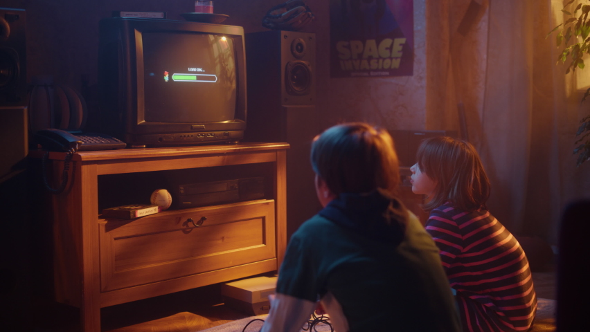 Nostalgic Childhood Concept: Young Boy and Girl Playing Old-School Arcade Video Game on a Retro TV Set at Home in a Room with Period-Correct Interior. Kids Pass the Level and Win. Royalty-Free Stock Footage #1091320813