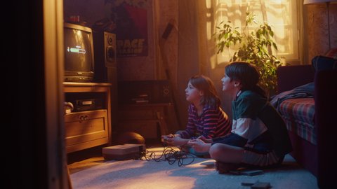 Nostalgic Childhood Concept: Young Brother and Sister Playing 8 Bit 2D Arcade Video Game on a Retro TV Set at Home in a Room with Period-Correct Interior. Friends Win the Level and High Five.