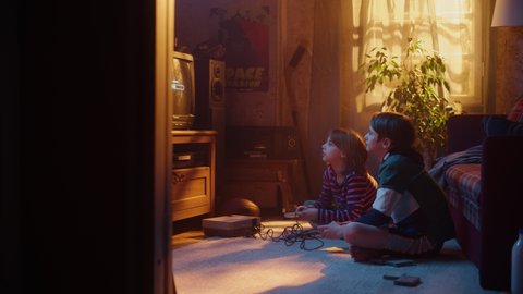 Nostalgic Childhood Concept: Young Brother and Sister Playing Old-School Arcade Video Game on a Retro TV Set in a Living Room with Period-Correct Interior. Friends Spend the Day at Home Playing Games.