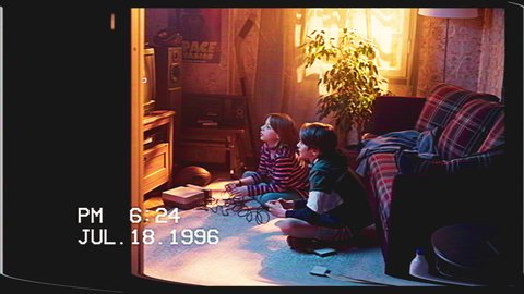 Retro VHS Tape Effect Home Video Concept: Young Brother and Sister Playing Old-School Arcade Video Game on a TV Set and Console at Home. Happy Kids Turn Around and Wave at the Camera.