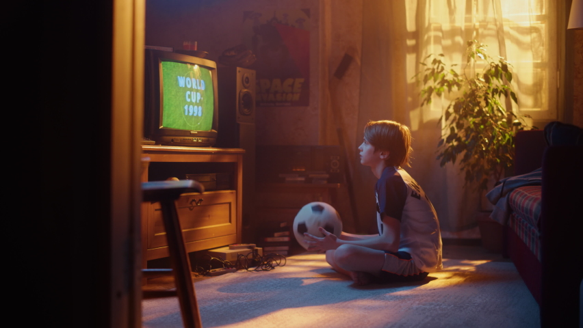 Young Soccer Fan Watches a World Cup 1998 Match on TV set at Home. Excited Boy Supporting His Favorite Football Team, Feeling Proud When Players Score a Goal. Nostalgic Retro Childhood 80s, 90s, 00s, Royalty-Free Stock Footage #1091320877