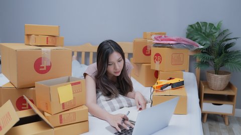Business concept of 4k Resolution. Asian woman checking customer orders at home. delivery of goods to customers.