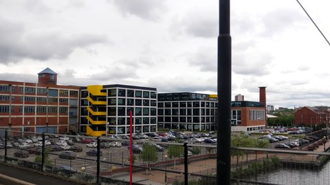 Tram passenger window view of car park for businesses near famous Media city in regenerated Salford area when crossing Manchester Ship Canal.