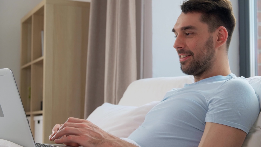 People, technology and remote job concept - man with laptop computer lying in bed at home bedroom | Shutterstock HD Video #1091333585