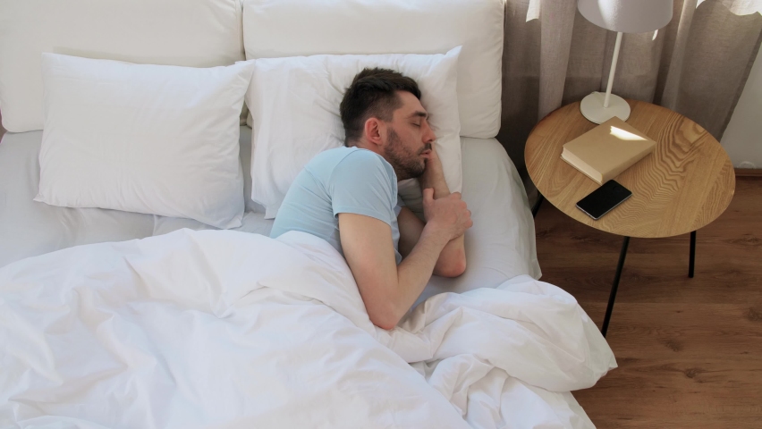 People, bedtime and rest concept - man sleeping in bed and checking time on smartphone at home | Shutterstock HD Video #1091333587