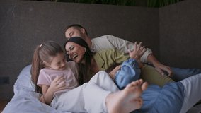 Happy young family with two children lying on bed at hotel, summer holiday. - Powered by Shutterstock - Get 15% off with code: PIKWIZARD15