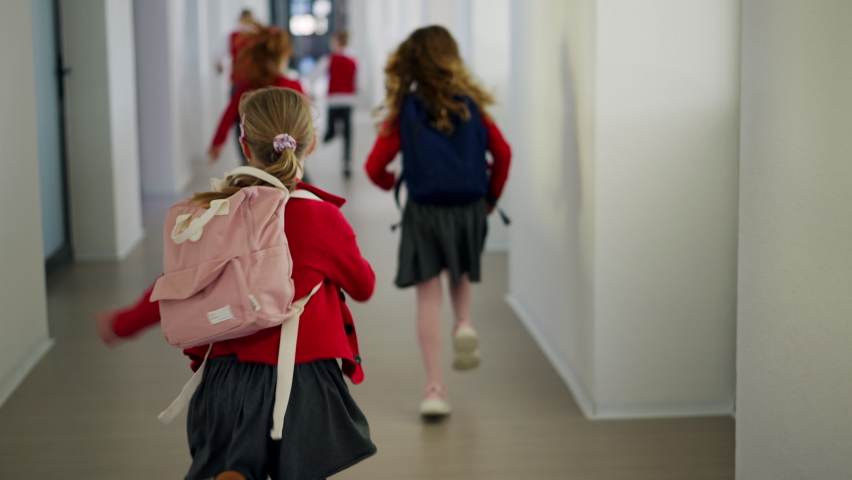 Rear view of schoolchildren in uniforms running in school corridor. Royalty-Free Stock Footage #1091336631
