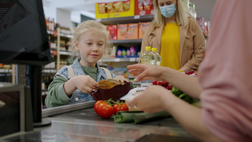 Close-up of little blond girl paying for grocery shopping in supermarket. Royalty-Free Stock Footage #1091336673