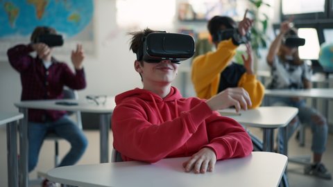 Teenage students wearing virtual reality goggles at school in computer science class Stockvideó