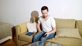 Young man switch at living room. Home vacation sofa portrait. Watch tv video. Alone in interior. Happy emotion. Smiling male person. Lifestyle action. House light background