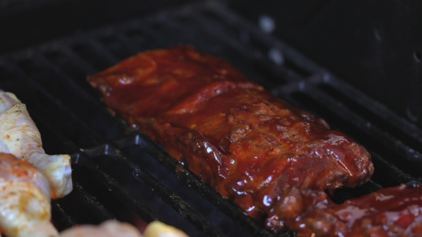 This close up, delicious video shows grill flames rising around bbq ribs on an outdoor grill in slow motion. Royalty-Free Stock Footage #1091340175