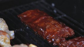 This close up, delicious video shows grill flames rising around bbq ribs on an outdoor grill in slow motion.