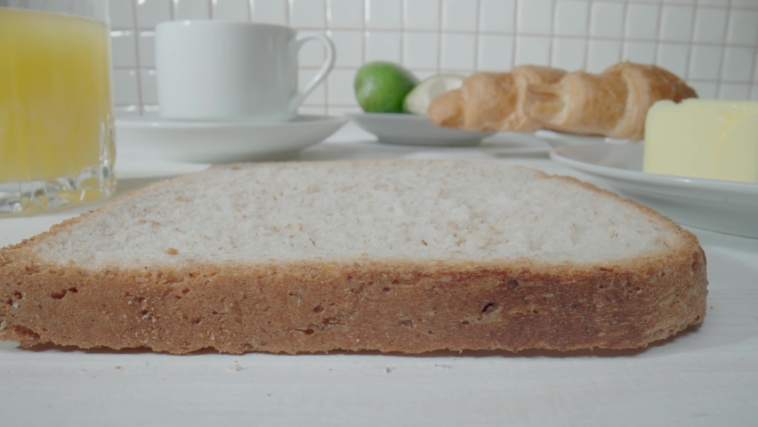 A stream of raspberry jam flowing from a jar onto piece of bread toast. Close up of sandwich with sweet jam. Cooking delicious breakfast in the morning in the kitchen. Sweet dessert, yummy, fast food.