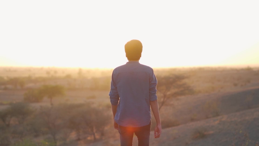 Portrait of an Indian man walking in front of sun during the sunset. Lonely man walks during the sunset. Loneliness concept. Man walks alone to think for his future. | Shutterstock HD Video #1091347967