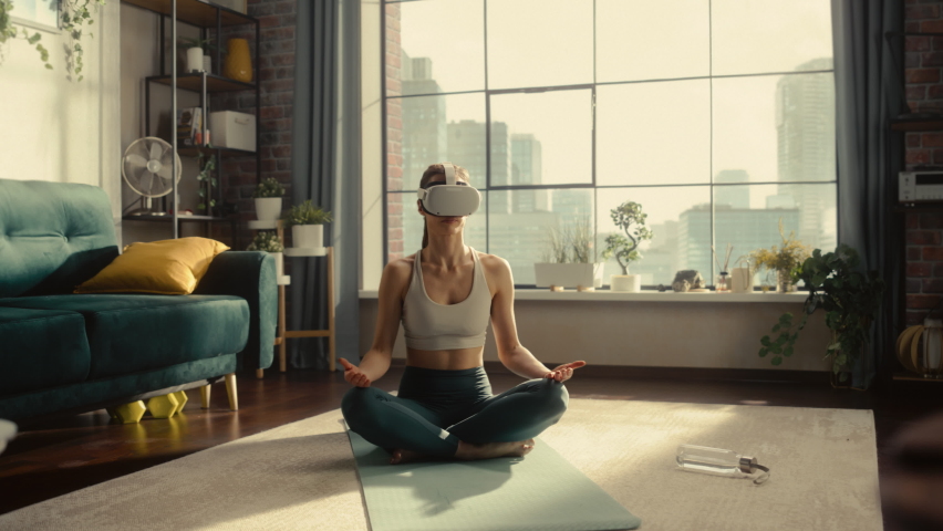 Young Athletic Woman Wearing Virtual Reality Headset, Practising Meditation in Modern Futuristic Way. She Sees Beautiful Idyllic Forest, Singing Birds and Peaceful Nature. Technology and Mindfulness. Royalty-Free Stock Footage #1091356009