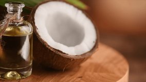 Coconut oil in a bottle with coconuts and green palm tree leaf rotated over brown background. Tropical Coco nut closeup. Healthy Food, skin care concept. Vegan food. 4K UHD video. 