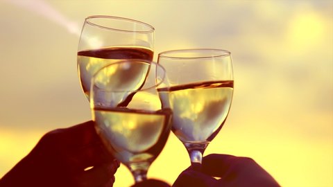 People holding Glass of Wine, Making a toast over Sunset sky. Birthday. Friends drinking White Wine, toasting. Clink. Party outdoors. Enjoying time together. Slow motion