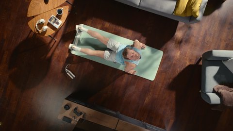 Top View Sport: Attractive Guy Doing Yoga Stretching on an Exericise Mat at Home. Muscular, Fit, Handsome Athletic Man Does Fitness Workout in His Apartment. Top Down Zoom Out Slow Motion Spin Shot