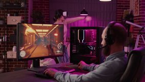 Gamer streaming first person shooter on pc while woman uses vr goggles for simulation in living room. Man playing multiplayer online action game while gaming girl is fighting in virtual reality game.