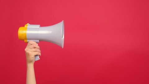 Close up of woman hand holding bullhorn public address megaphone, Hot news, announce discounts sale, hurry up, isolated over red background with copy space for advertisement. Communication concept