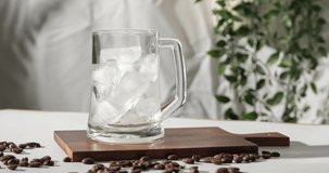 4k video, pouring brewing coffee into glass full of ice. Making cold coffee drink in slow motion. 