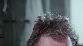 The man is drying his crazy hair, thinning hair. Slow motion video.