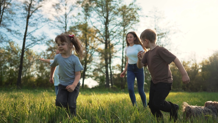 Children play in spring vacation park.Active happy group of kid run with a dog on grass in field in summer.Family in nature with pet.Child on play.Happy family concept.School in garden with dog Royalty-Free Stock Footage #1091379733