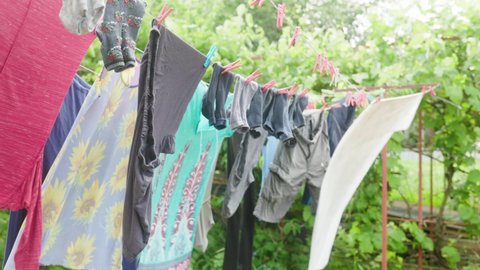 the washed laundry hangs on a rope and is dried. freshly washed pants and shirts and T-shirts dry outdoors in the open air outdoor