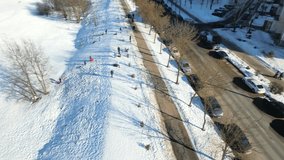 People (children and adults) ride in the winter on a hill on tubes and sleds. Sports winter sports, winter recreation. Construction aerial view height, drone video	