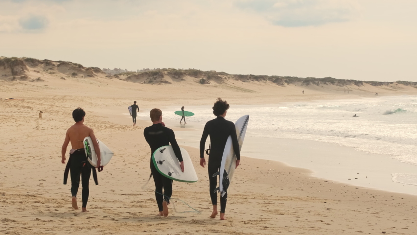 Unidentified surfers with surf board walk on the Baleal beach and watching other surfers catching waves. Baleal is a popular surfing spot in Portugal.  | Shutterstock HD Video #1091386845