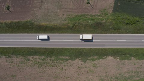 Aerial shot of commercial van and lorry truck on highway through countryside landscape, directly above drone pov. Transportation and traffic concept.