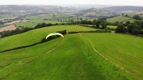 Parallax shot of a paraglider flying over the East Devon Countryside England