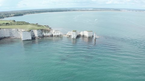 Low circling drone shot of Old Harry rocks chalk cliffs Dorset UK