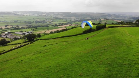 Aerial shot of a Paraglider flying over a field and Countryside in East Devon England