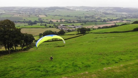 Aerial parallax shot of a Paraglider taking off from a hill in Devon England