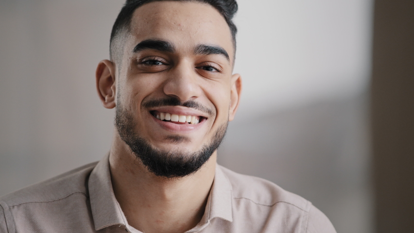 Dreaming arabic handsome young man agent worker deep in thoughts look away turn head at camera happy male human face friendly businessman millennial 20s guy smiling with toothy smile close up portrait | Shutterstock HD Video #1091400145