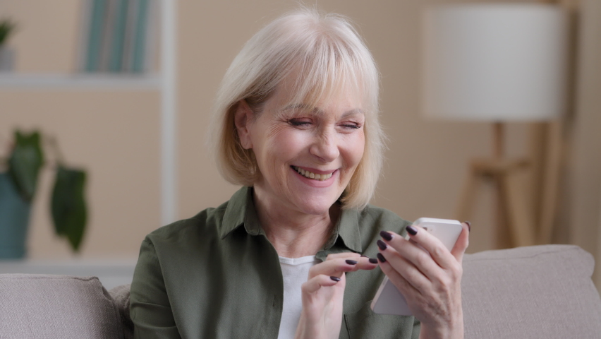 Close up happy excited successful amazed old emotional woman receive good news offer money prize achievement with phone smiling rejoice showing thumb up sitting on sofa with smartphone winning online - Powered by Shutterstock - Get 15% off with code: PIKWIZARD15