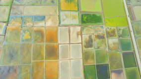 4K aerial view from a drone flying over a beautiful colorful natural sea salt pond. Salt field at Mae Klong, Samut Songkhram, Thailand. Primary production in the industry. Farm field outdoor. 
