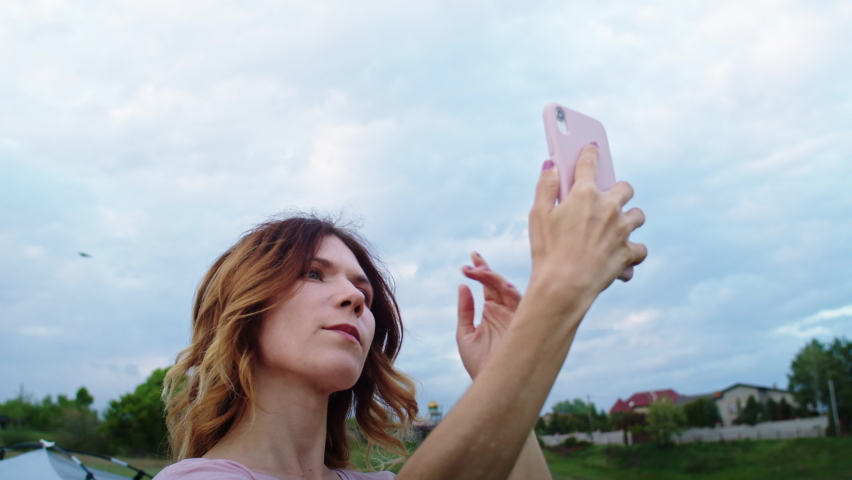 a young woman is happy to communicate in video communication through a phone on the mountain hills during sunset, for relaxation after a hike. rest of one person in nature, in the mountains.