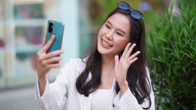 attractive asian woman pleased positive casual shopping hand hold paper bags and smartphone enjoy purchase cloths and video calling friend at center mall store shopfront corridor department store