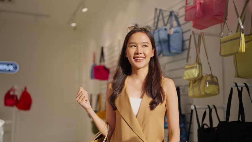happiness smiling Young happy beautiful asia woman holding colorful shopping bags while open the shopping mall glass entrance door shopfront store,Woman leaving a store with shopping bags