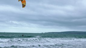 People kite boarding in the sea with huge waves. 4k video.