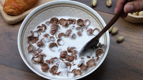 4k-Top view slow motion of hand stirring cereal with milk on wooden background, healthy breakfast concept.