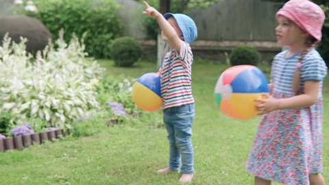 Happy Children runing with Multi-Color Beach Ball and Soap Bubbles. Mother, Daughter and Son Have Fun Playing Games in Backyard Lawn of Idyllic Suburban House on Summer Day. Childhood, family concept