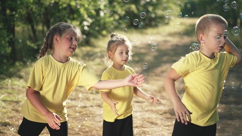 Happy child with toothy smiles. Boy and girl show soap bubbles. Kid catch soap bubbles with their hands. Child in nature are play and having fun. Summer family dream in park. Green grass on sunny day